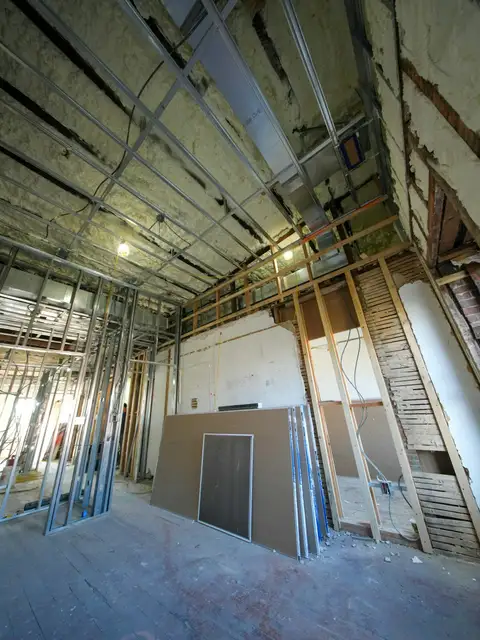 Metal stud framing with drywall sheets stacked ready to hang